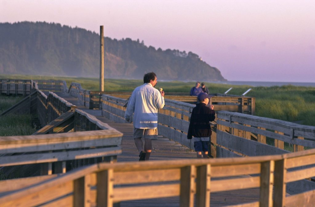 Father and son enjoying a sunset walk on the Long Beach Boardwalk, one of the top things to do in Long Beach, Washington.