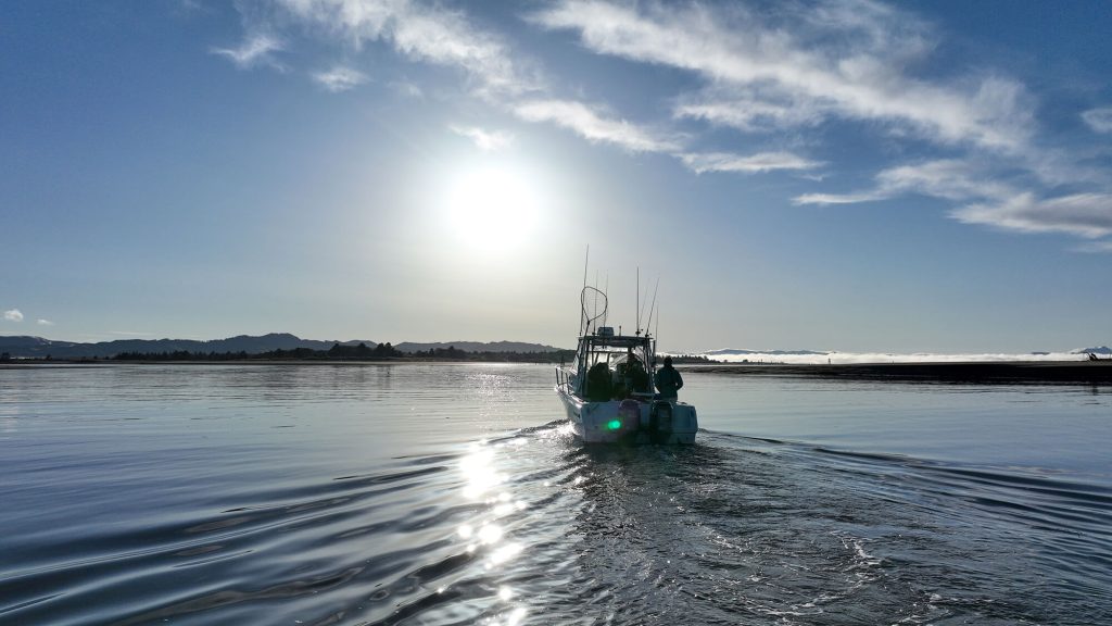 A fishing boat on a large body of water and mountains in the distance.