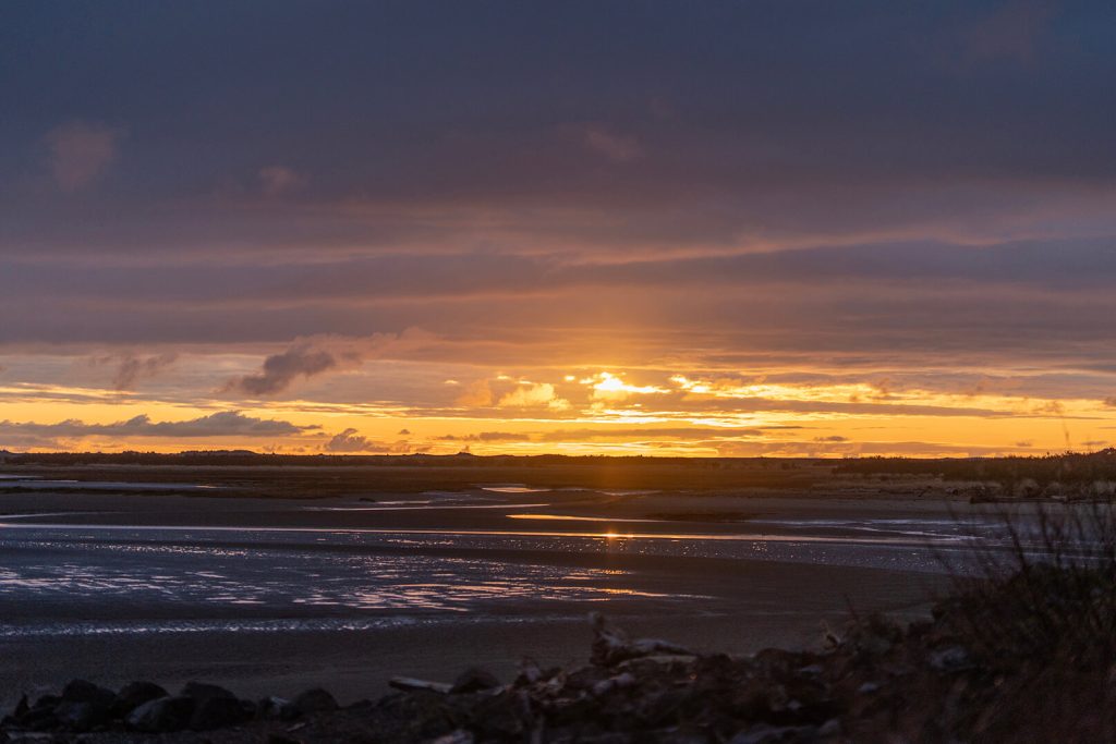 A wide shot of a beach at sunset.