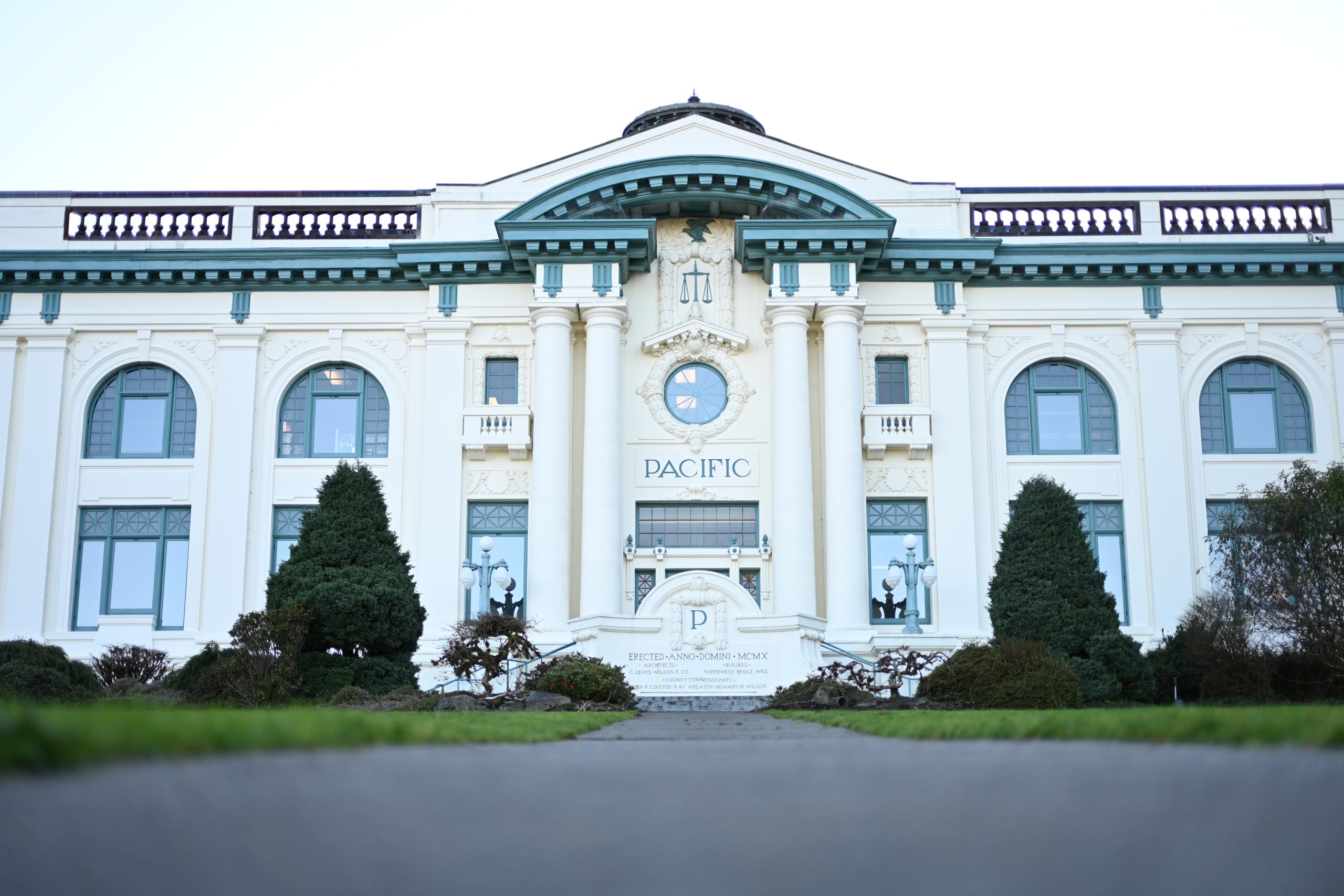 A front view of the Pacific County Courthouse and a row of trees and bushes out front.