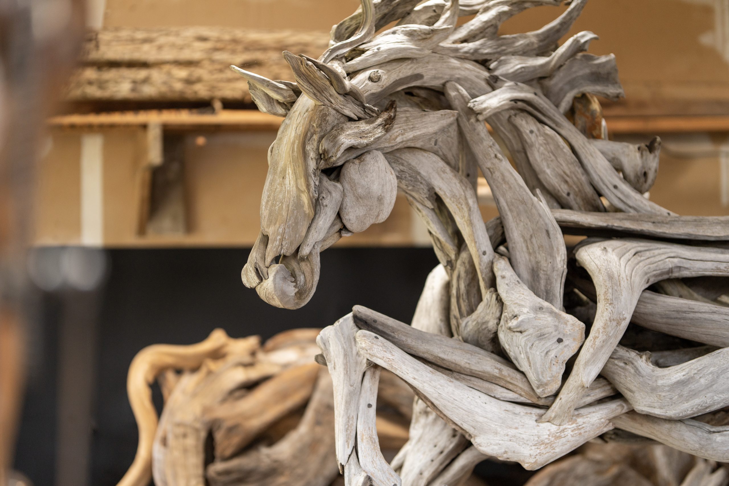 A driftwood sculpture of a galloping horse inside a workshop.